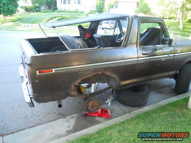 Brown 1979 Ford Bronco side view, soft top removed, undergoing repairs with wheels off