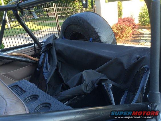 Interior of a soft top vehicle showing a spare tire and folded top