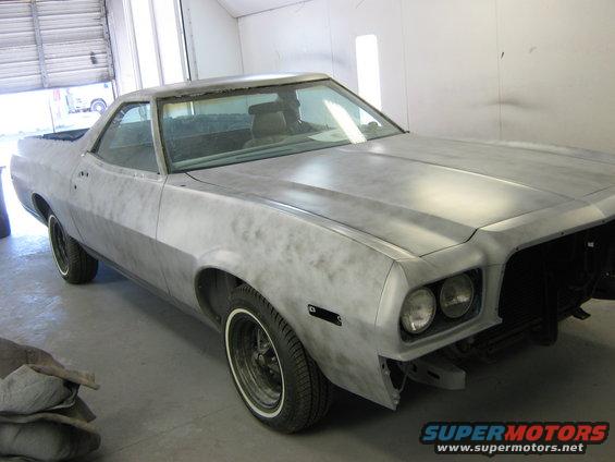 Primer-covered coupe utility vehicle, likely a 1972 Ford Ranchero, in a garage. Front end is partially disassembled