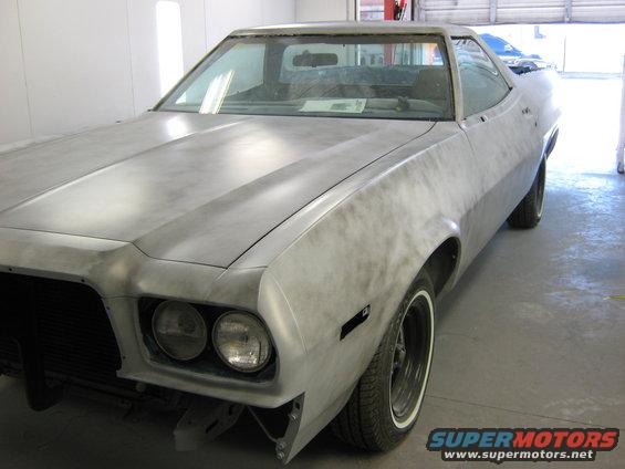 Unpainted car body, front 3/4 view, showing dual headlights and a prominent hood crease