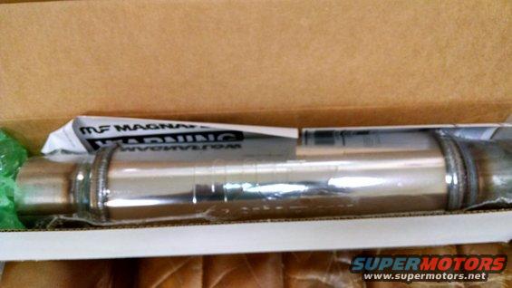 Chrome exhaust muffler in a cardboard box, with "MF MAGNAFLOW WARNING" text visible