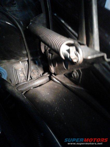 Close-up of a car's hood latch mechanism with a spring