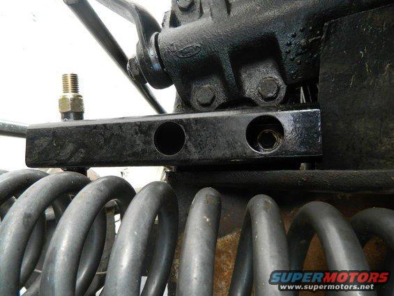 Black metal bracket with bolt holes above grey coil springs