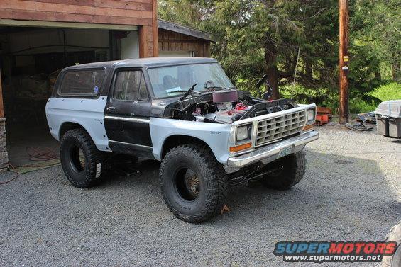 Ford Bronco with hood open, light blue fenders, black body, and large tires