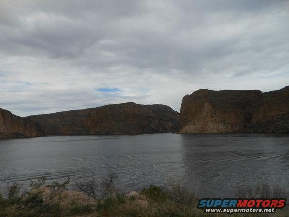 calm lake with rocky hills under cloudy sky
