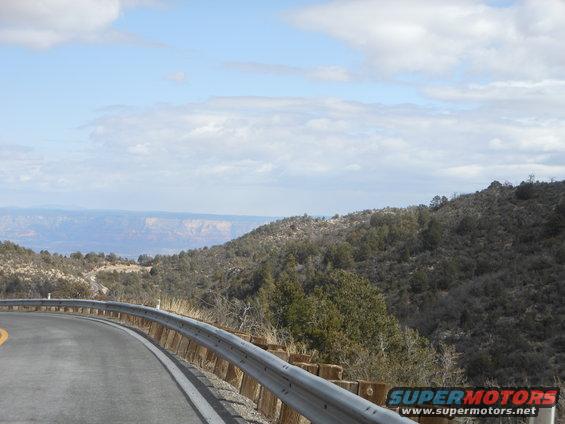 Roadside guardrail with distant canyon view under cloudy sky