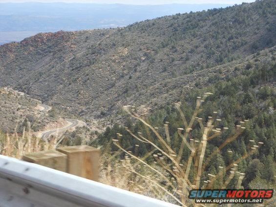Winding mountain road through a valley with trees and scrub brush