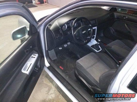 Silver car interior with black dashboard, Audi steering wheel, and GTI floor mats