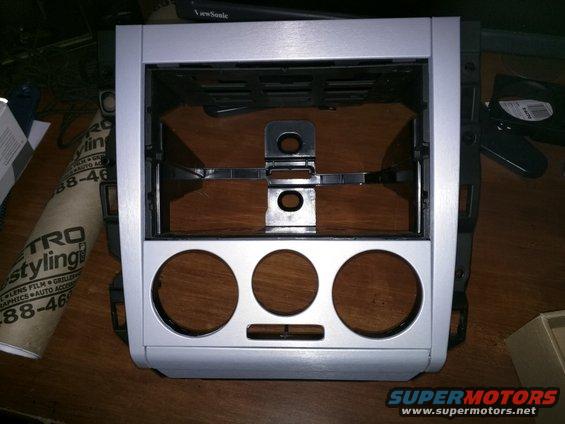 Car stereo dash mounting bracket with three circular cutouts and a rectangular slot
