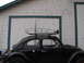 1964 Volkswagen Beetle - A black 1964 Volkswagen Beetle with a roof rack is parked in front of a white wooden garage door.