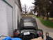 1964 Volkswagen Beetle - The rear of a black Volkswagen Beetle is visible, with its engine compartment open and a roof rack mounted on top.