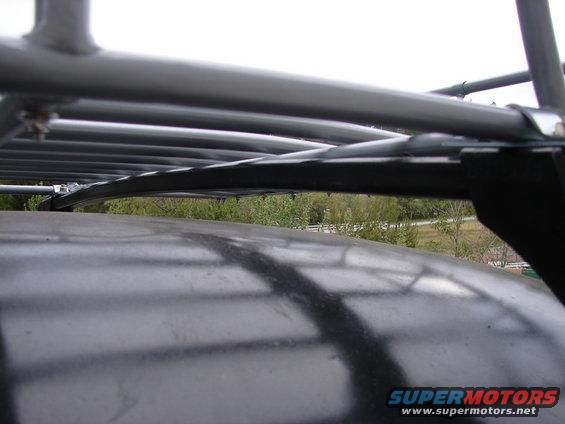 Close-up of a car's roof rack, showing metal bars and straps over the dark roof
