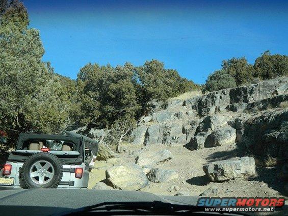 Silver Jeep Wrangler on a rocky trail, going uphill