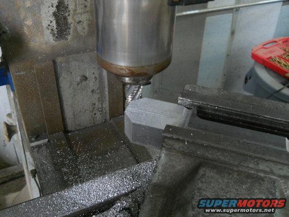 Milling machine cutting a hexagonal metal part with metal shavings on the table