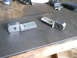 1992 Ford Bronco - Two machined metal parts are shown on a workbench surface, with tools visible in the background.