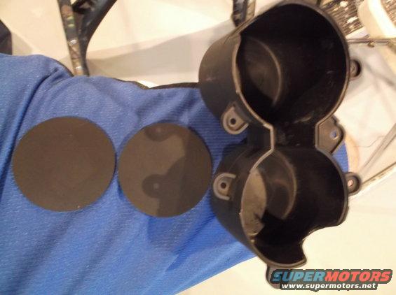 Black plastic gauge cluster housing with two circular trim rings on a blue cloth