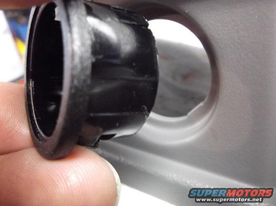 Close-up of a black plastic car interior trim piece being held by fingers