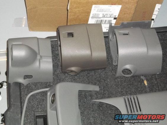 Gray and tan plastic steering column covers laid out on a gray carpeted surface