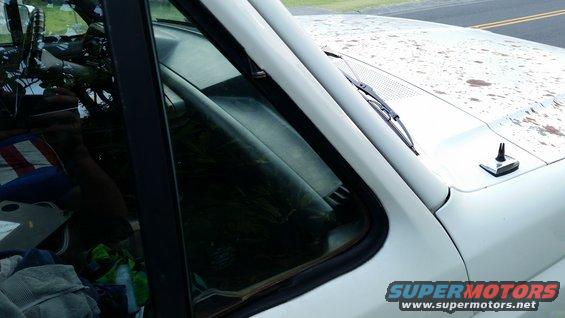View inside a white SUV, looking past the windshield at the dashboard and seats. The hood is visible with rust spots