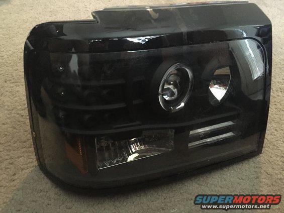 Black aftermarket headlight assembly with projector lens and LED accents