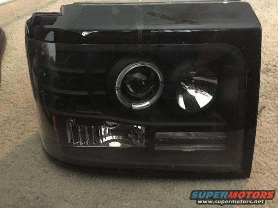 Black aftermarket truck headlight with projector lens and halo ring