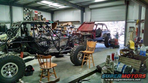 Buggy project in foreground, Jeep project with hood up in background, inside garage