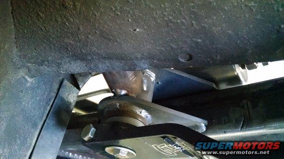 Close-up of a black suspension bracket with visible bolts and a metal plate welded to a tube