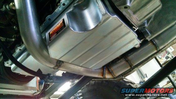 Underbody view of a vehicle showing an aftermarket exhaust system and a polished aluminum oil pan with an "AUTOKRAFT" logo