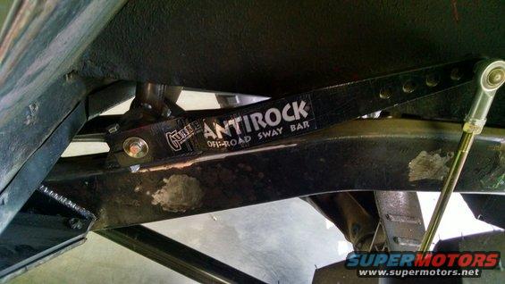 Black Antirock off-road sway bar with white lettering, mounted to vehicle frame