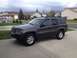 2004 Jeep Grand Cherokee - This 2004 Jeep Grand Cherokee is shown from a three-quarter front view, parked on a concrete driveway in a residential area.