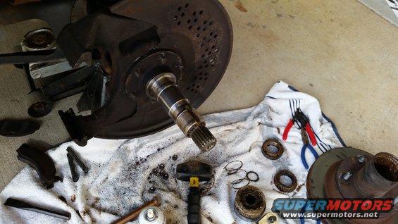 Disassembled wheel hub, brake rotor, bearings, and tools laid out on a towel