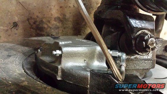 Brake caliper assembly on a vehicle part, with a braided metal brake line attached
