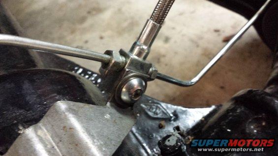 Close-up of a brake caliper with braided brake line attached to a metal bracket