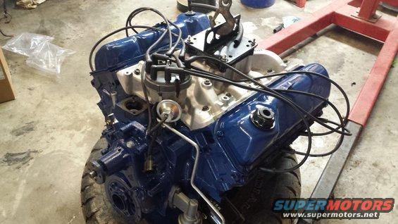 Blue Ford V8 engine on an engine stand, with distributor and intake manifold visible