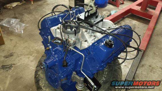Blue V8 engine on a tire, with a red engine hoist in the background
