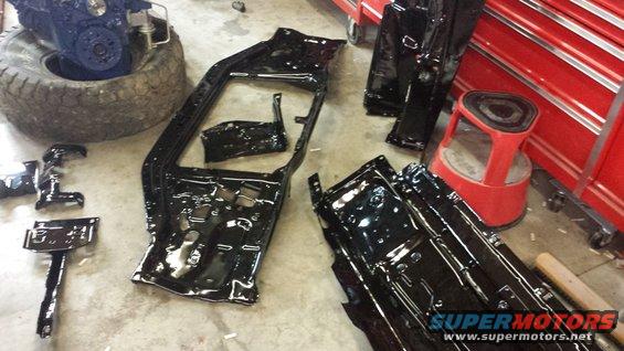 Black painted vehicle frame sections and an engine block on a tire