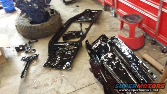 Engine on a tire, vehicle frame, and other parts laid out on a garage floor