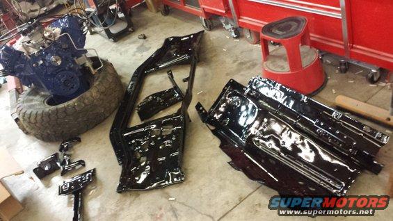 Engine and black painted vehicle body panels on a garage floor