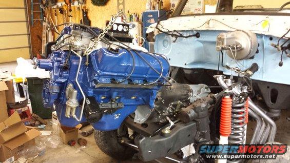 Blue engine being installed in vehicle chassis with red shock absorbers