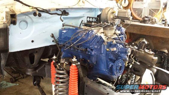 Engine bay with a blue Ford V8 engine and red shocks. Supermotors.net logo visible