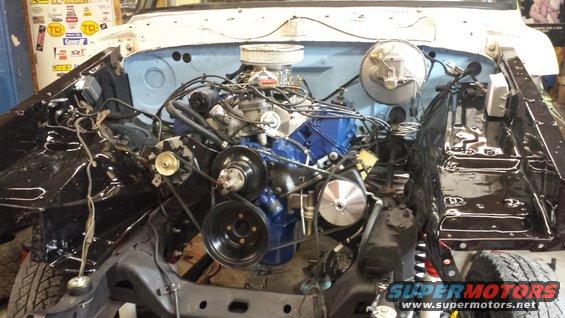Engine bay of a white vehicle, blue cap visible
