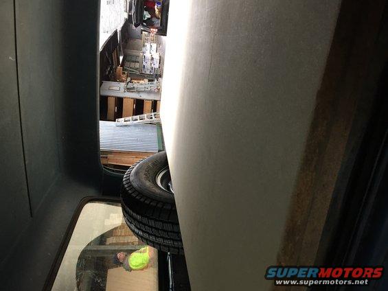 Spare tire mounted in cargo area of a vehicle, with a view of a workshop or storage area through a window