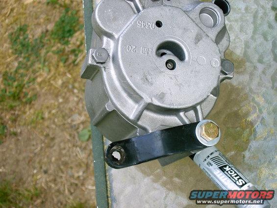 Close-up of a smog pump with a black bracket attached. A tube of anti-seize is also visible