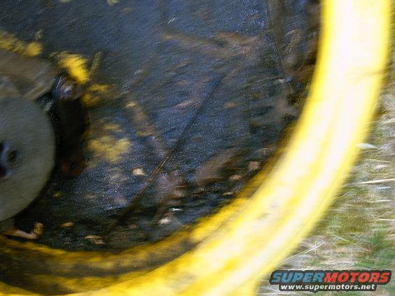 Close-up of a dirty smog pump with yellow casing and black debris