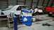 1985 Ford Escort - A blue engine is mounted on a stand in a garage, with a white car and red truck nearby.