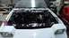 1985 Ford Escort - Engine bay of a 1985 Ford Escort undergoing work, with a spray can visible on the fender.