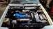 1985 Ford Escort - The engine bay of a car is shown with the hood open, revealing the engine and surrounding parts.