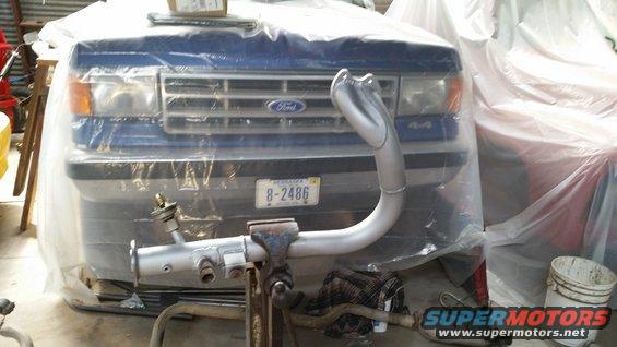 Blue Ford truck front end with "4x4" badge and "Ford" grille, covered in plastic