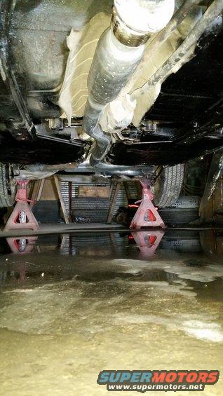 Undercarriage of a vehicle on red jack stands, with a driveshaft visible