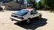 1985 Ford Escort - This two-tone coupe features a prominent rear spoiler and distinctive body lines, suggesting a model year around 1985.